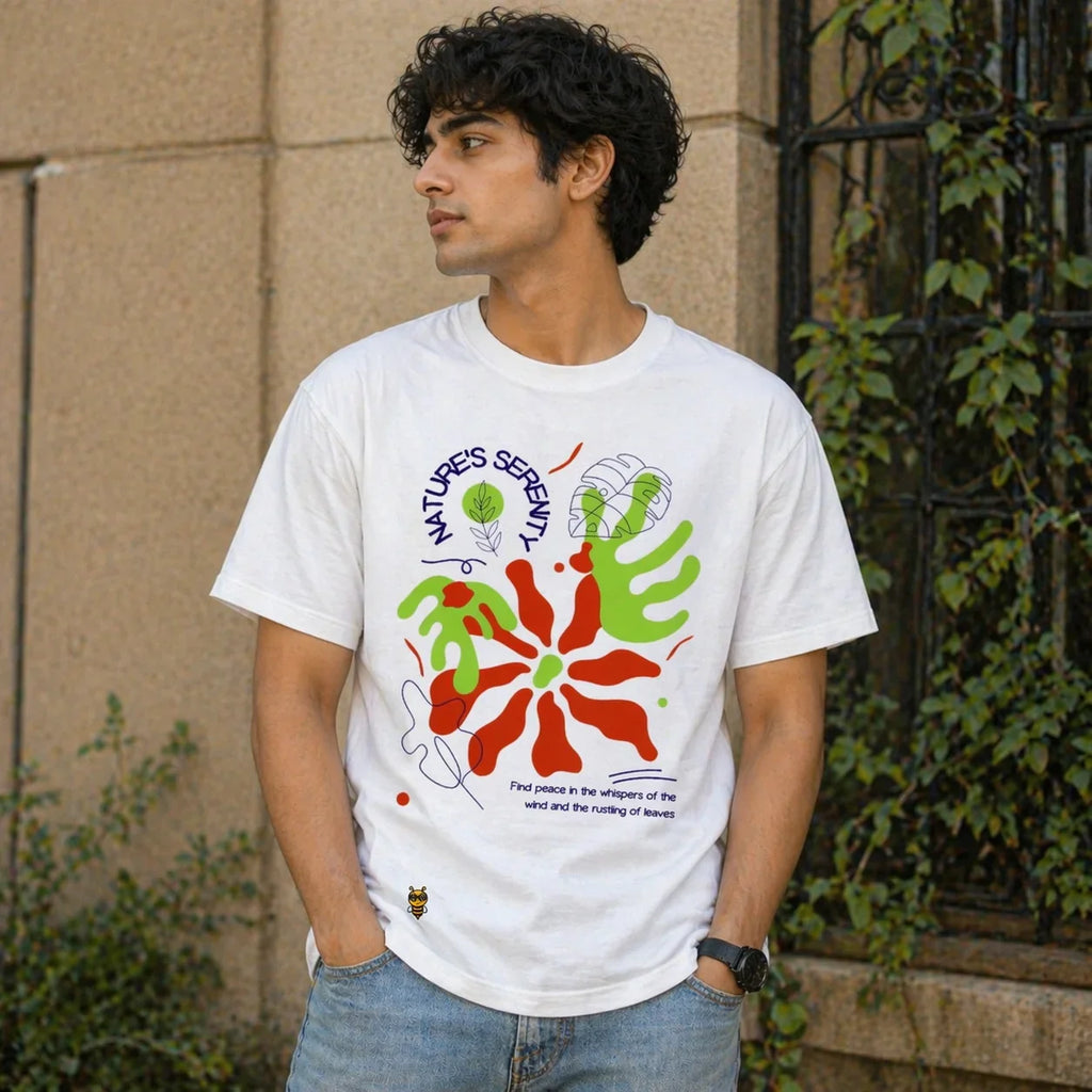 Man wearing oversized white graphic t-shirt with colorful nature-inspired print and text outdoors