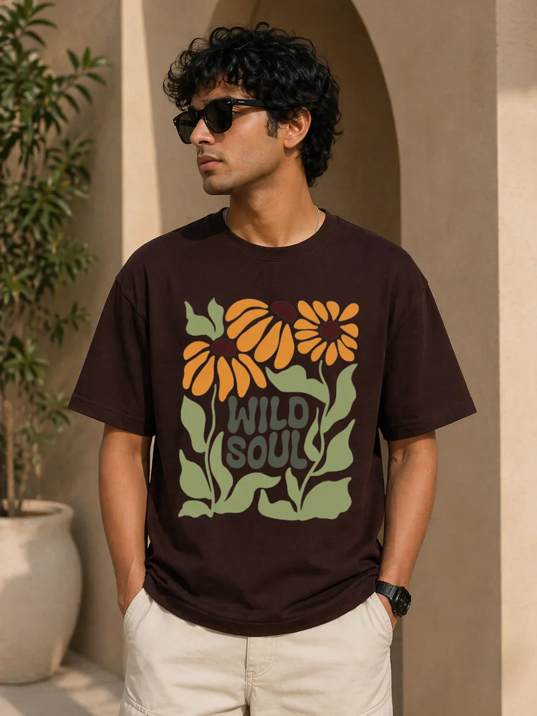 Man wearing dark brown oversized t-shirt with 'Wild Soul' floral graphic print, ideal for casual streetwear style.