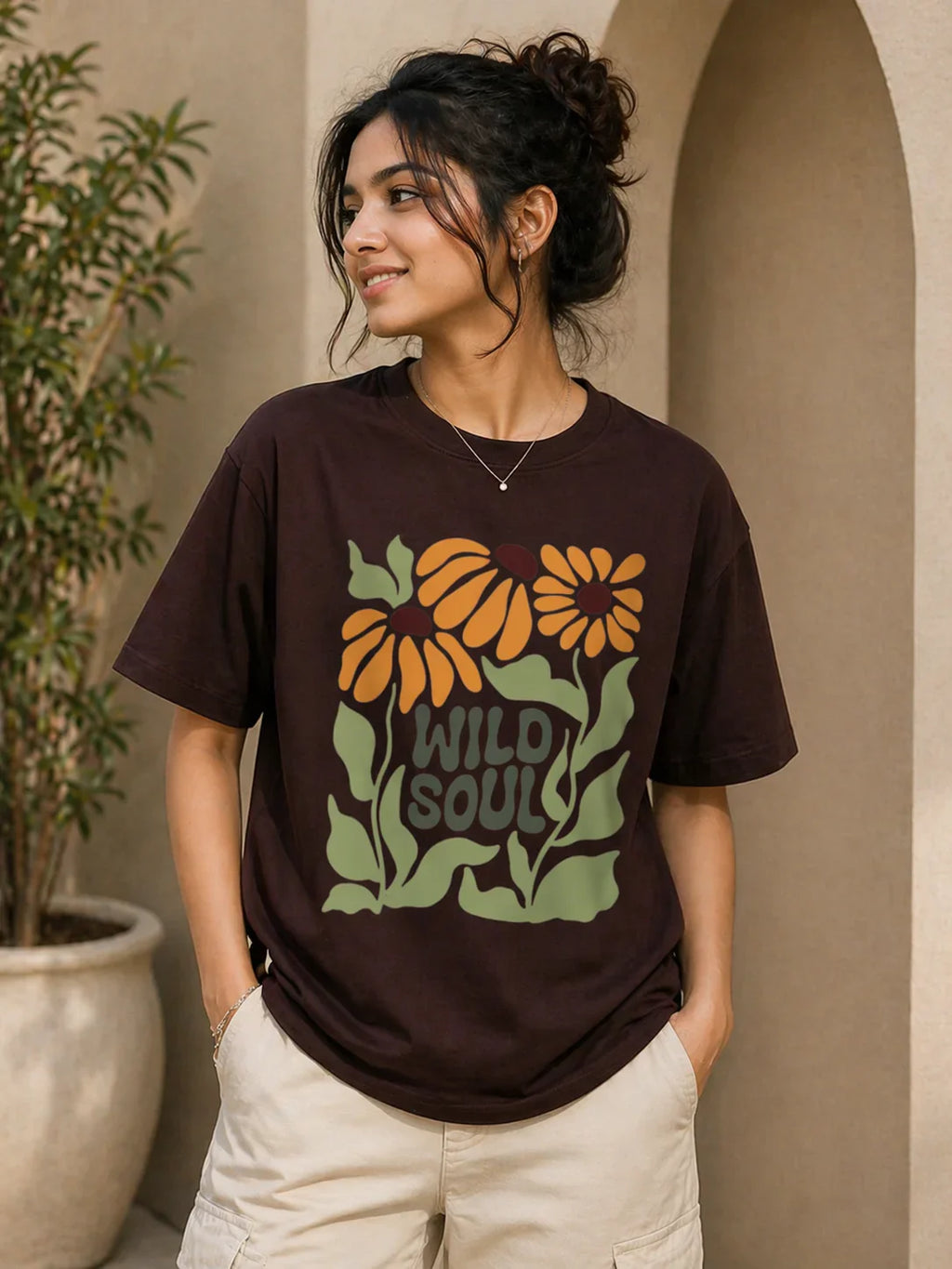 Brown oversized t-shirt with 'Wild Soul' floral graphic, worn by woman in casual outdoor setting