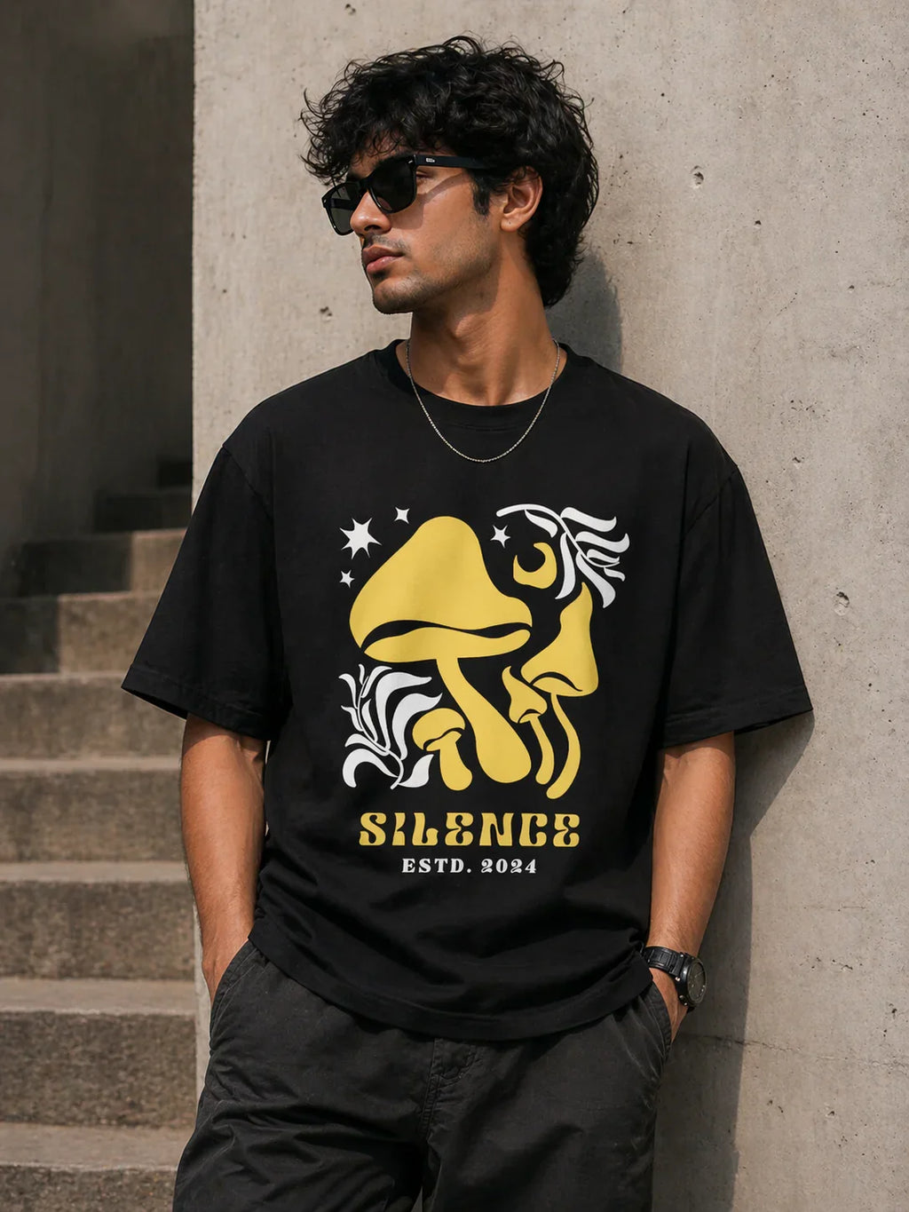 Man wearing black oversized t-shirt with yellow mushroom graphic and 'Silence ESTD. 2024' text