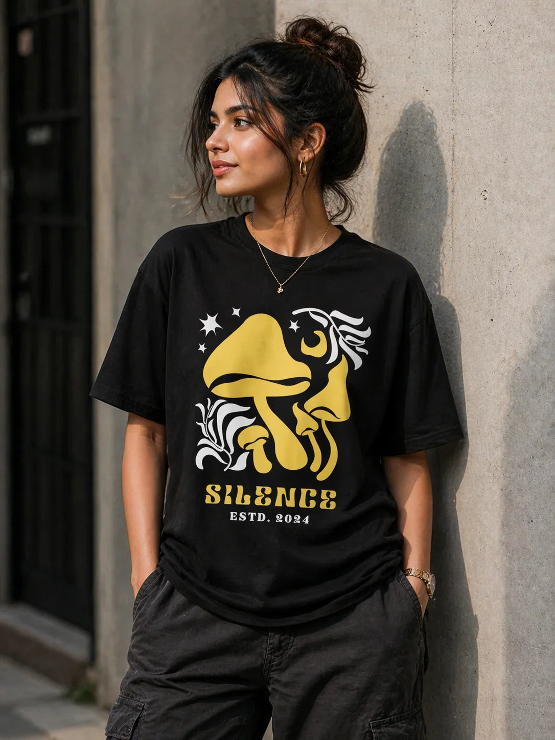 Woman wearing black oversized t-shirt with yellow mushroom graphic and 'Silence ESTD. 2024' print