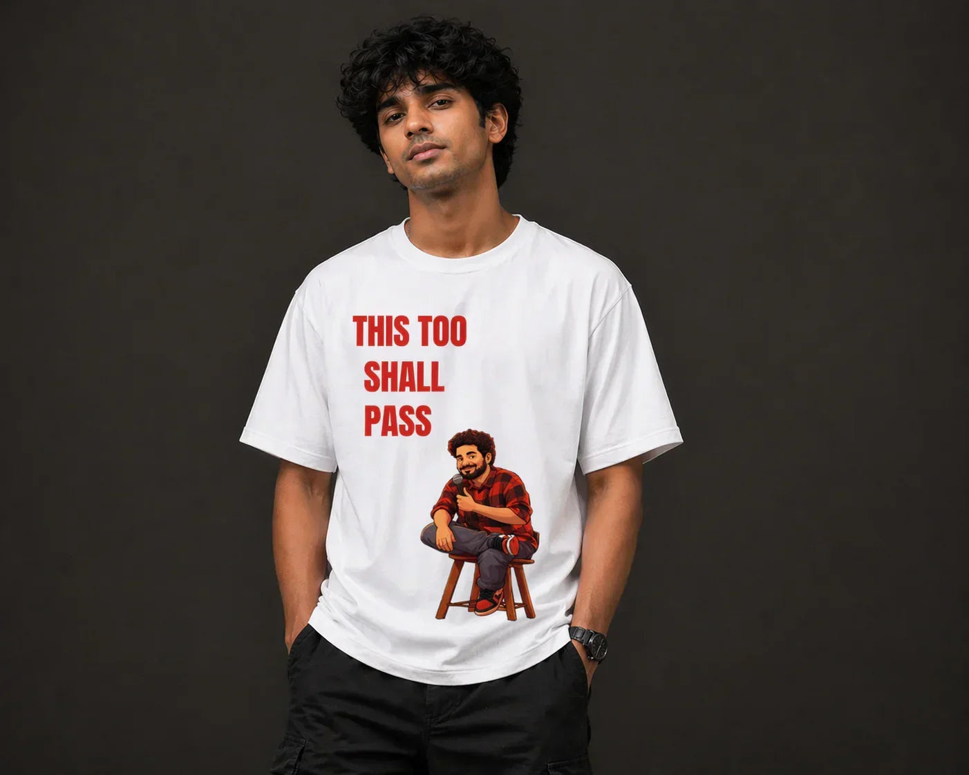 Man wearing oversized white t-shirt with cartoon graphic and 'This Too Shall Pass' text