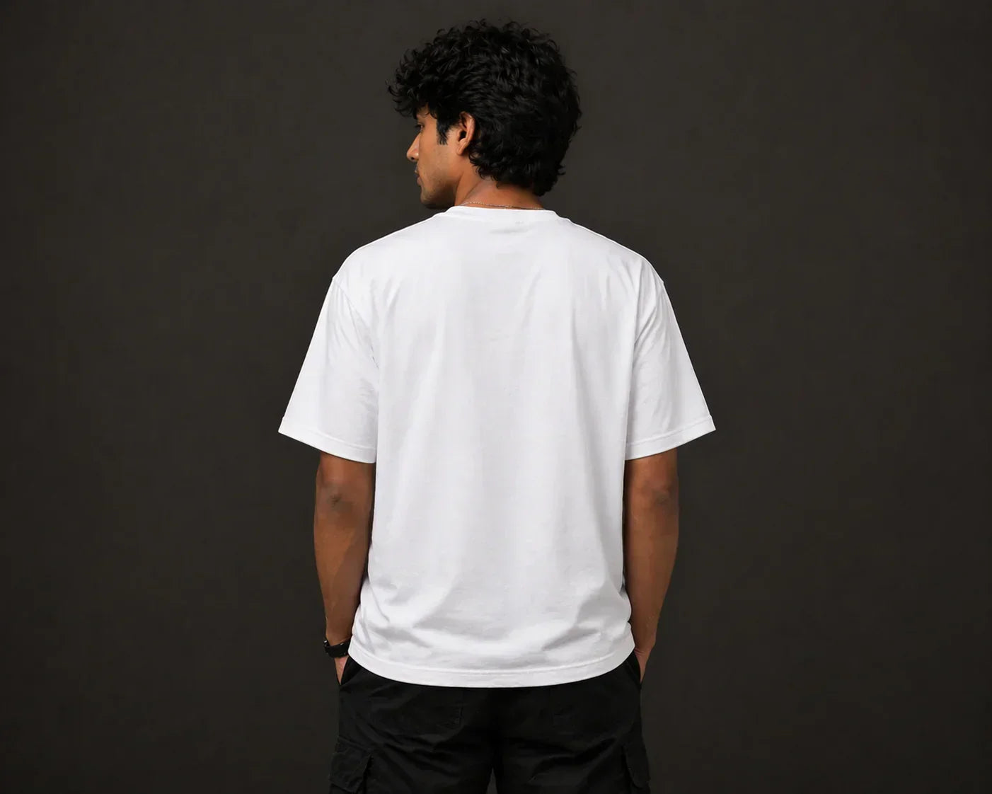 Man wearing plain white oversized t-shirt and black shorts, seen from the back