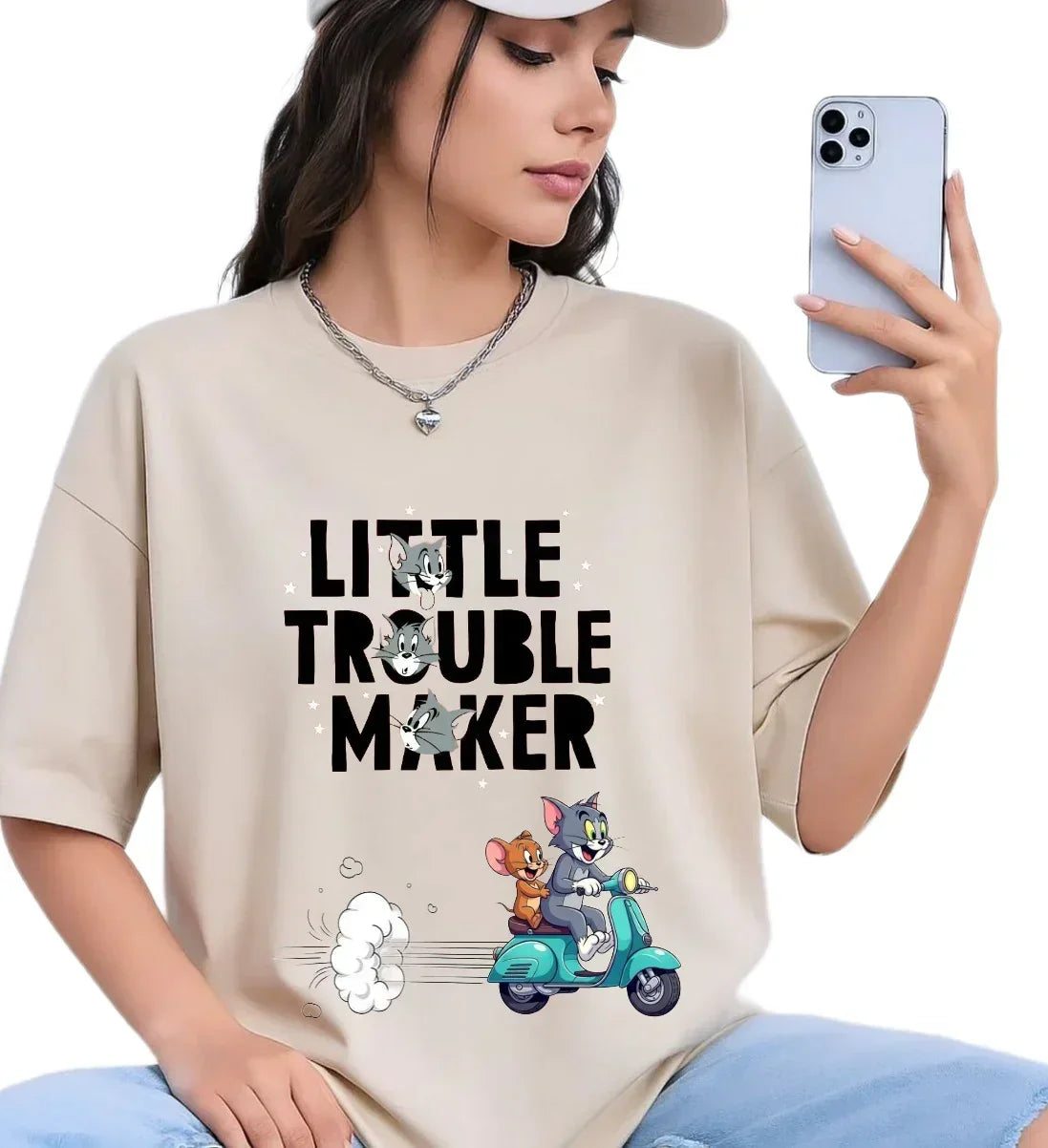 Woman wearing oversized beige t-shirt with Tom and Jerry cartoon print and 'Little Trouble Maker' text.