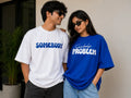 Man in white oversized t-shirt with 'Somebody' text and woman in blue 'Somebody’s Problem' t-shirt